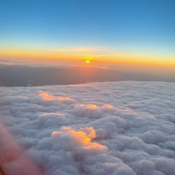 A breathtaking aerial view taken from a plane window, showcasing a vast expanse of fluffy white clouds beneath, illuminated by soft golden sunlight