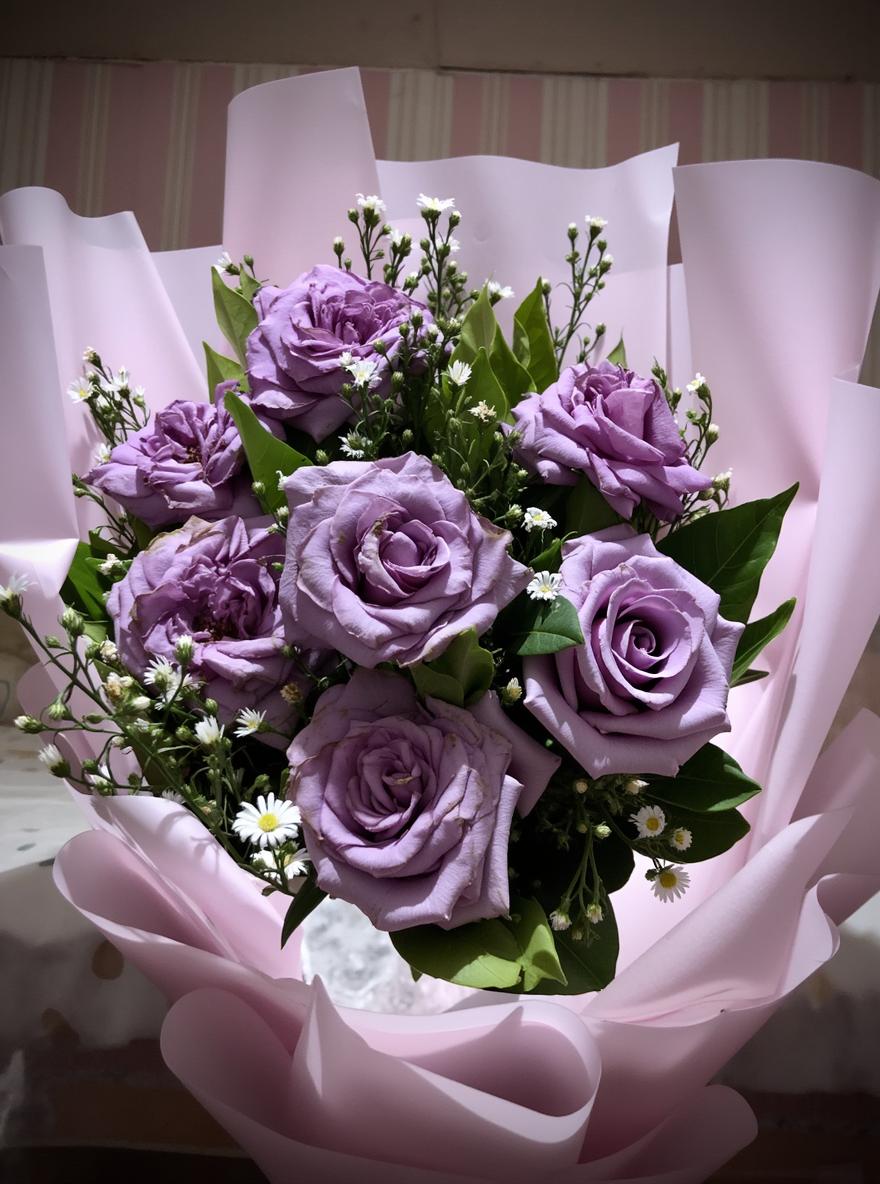 A beautiful, fresh bouquet of lavender roses arranged elegantly with delicate white baby's breath and lush green foliage