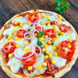 A delicious and vibrant pizza featuring a refreshing combination of crunchy onions, succulent juicy tomatoes, and sweet golden corn, all generously layered beneath a thick, gooey layer of melted mozzarella cheese
