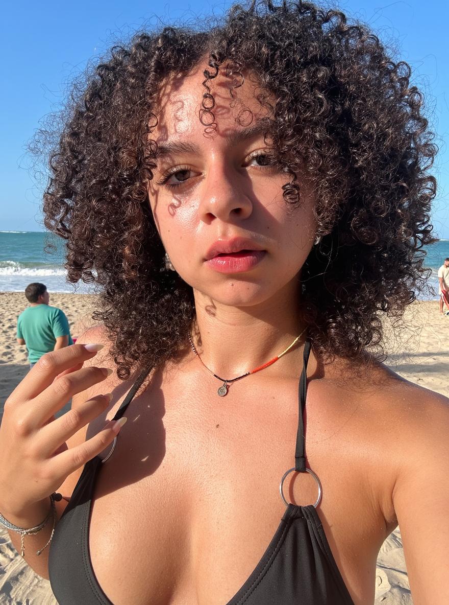 A close-up portrait of a young woman with curly hair, capturing the essence of a sunny day at the beach