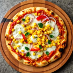 A delicious pizza featuring a mouthwatering topping of sweet corn, crunchy onions, and vibrant capsicum, all perfectly balanced on a base of melted mozzarella cheese