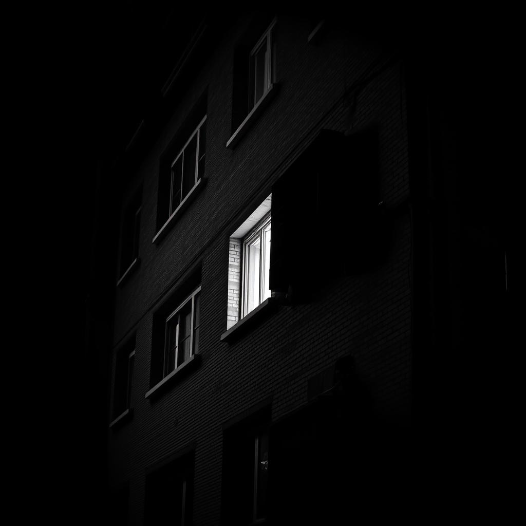 A striking black and white image of an apartment building, showcasing its architectural details with crisp lines and shadows