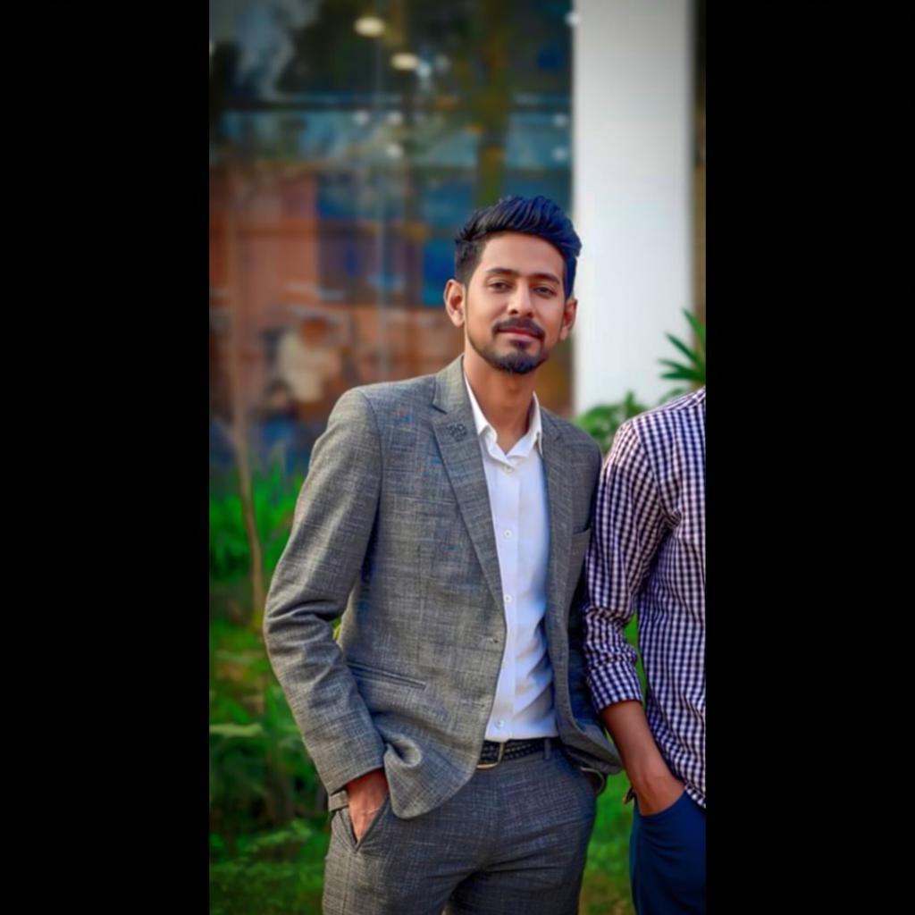A stylish young man dressed in a grey plaid suit, standing confidently with one hand in his pocket