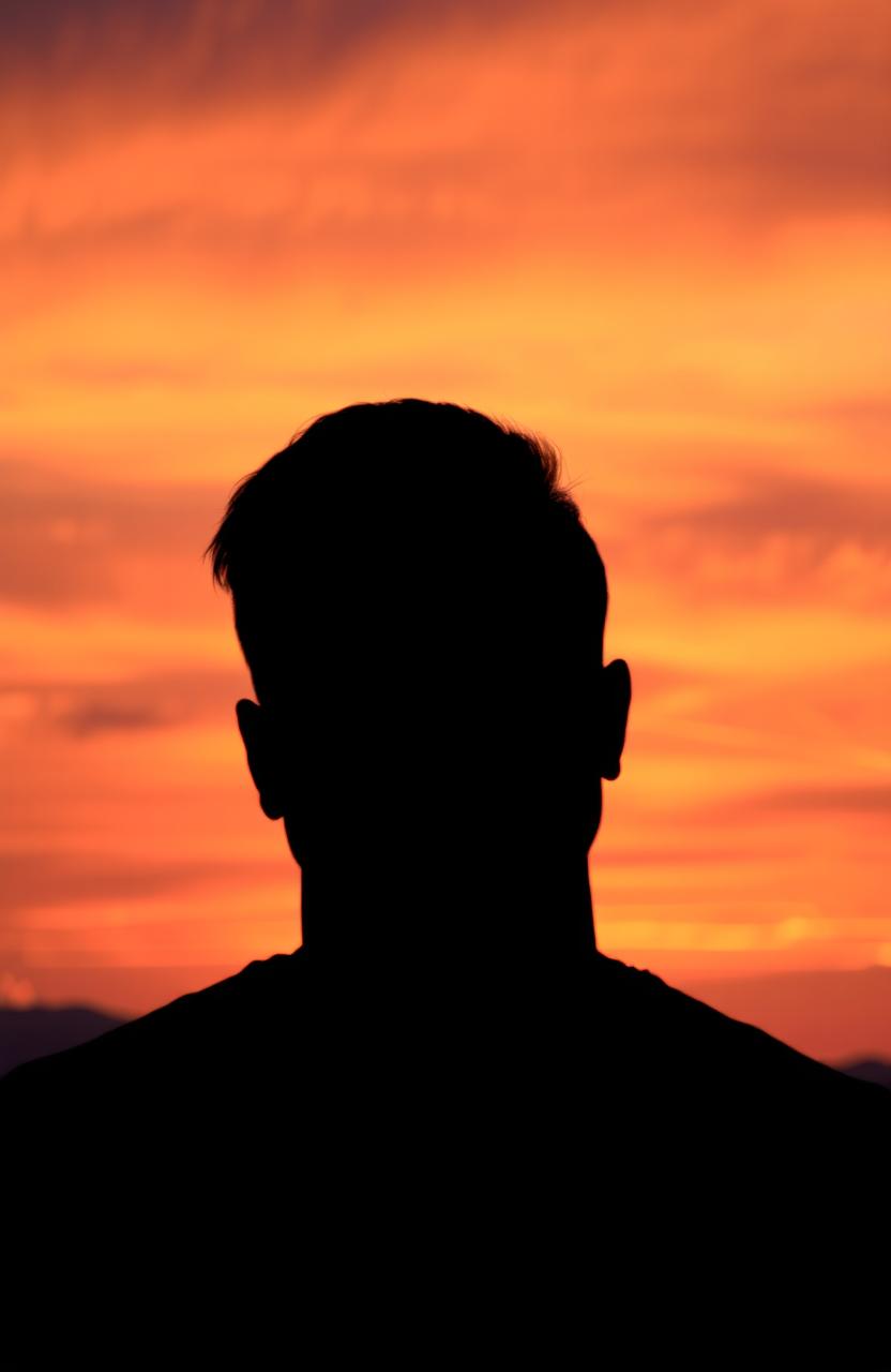 A captivating image of a prominent shadow of a face cast against a breathtaking sunset sky