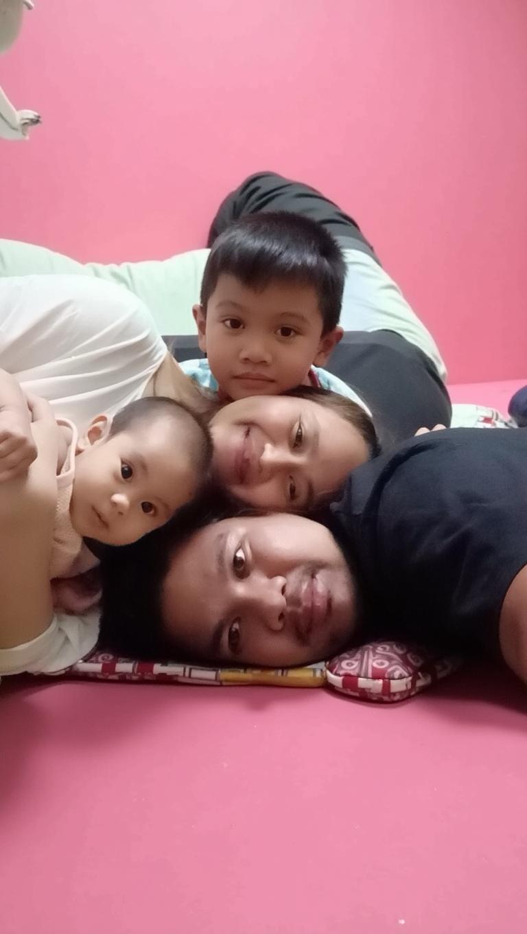 A heartwarming family portrait featuring a father lying on a bed, surrounded by three children