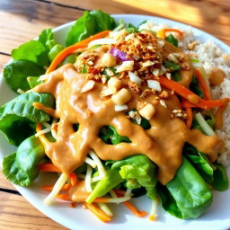 A beautifully arranged plate of Pecel Salad, showcasing a vibrant assortment of steamed vegetables including spinach, bean sprouts, and sliced carrots, all drizzled with a rich and creamy peanut sauce