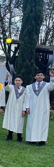 A celebratory graduation scene, featuring two young men in elegant white graduation gowns and matching caps