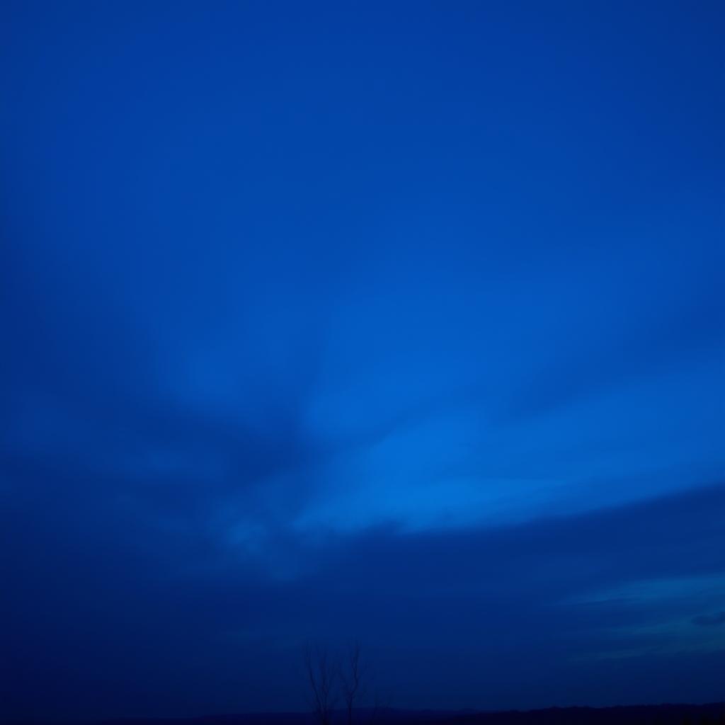 A captivating scene of a hazy, dark blue sky at dusk, featuring soft, wispy clouds that blend into a deepening twilight