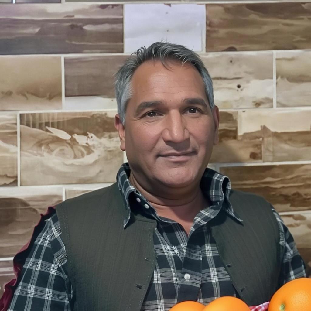 A man smiling warmly, holding a basket of vibrant, fresh apples in a rustic setting