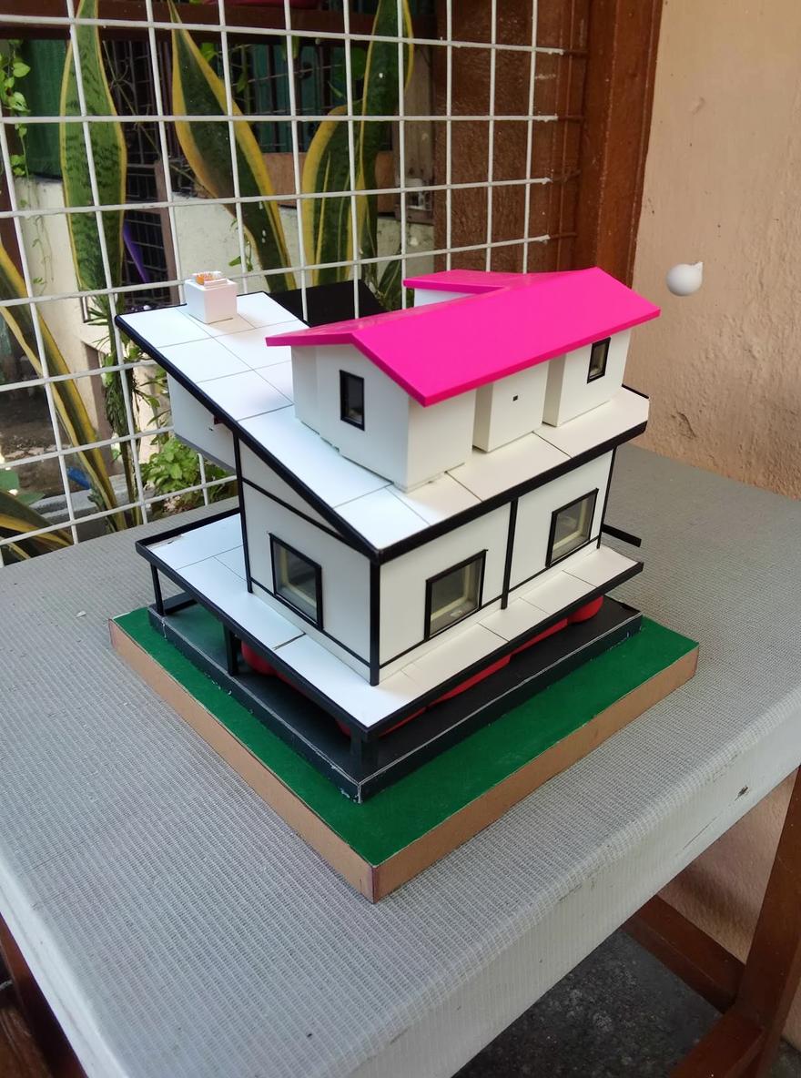 A model of a house design with a white exterior wall and a black glass frame