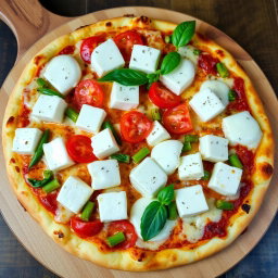 A mouthwatering pizza featuring soft, creamy paneer cubes, crunchy green capsicum, and juicy, ripe tomatoes, lavishly topped with gooey, melted mozzarella cheese