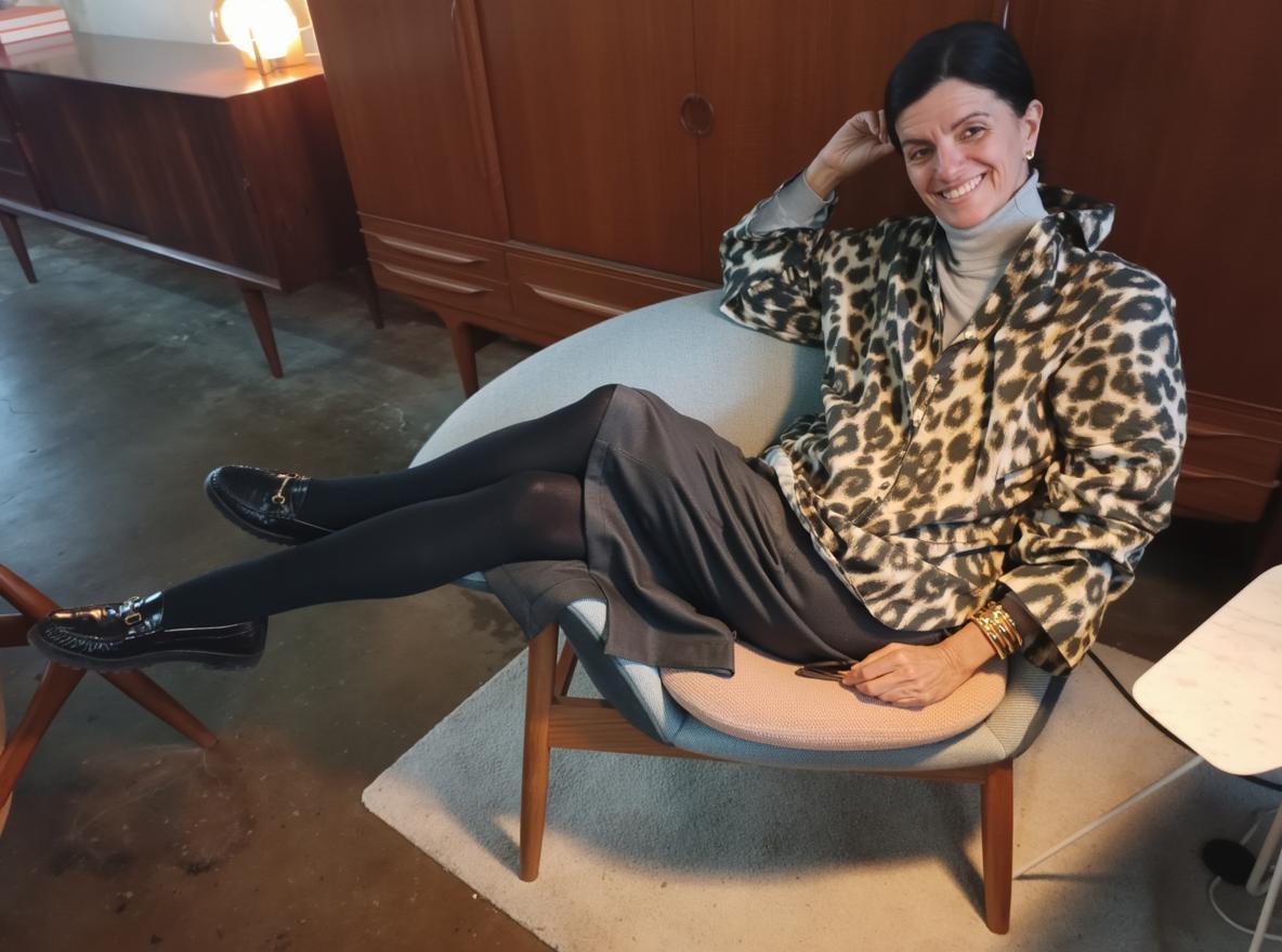 A woman seated comfortably in a stylish mid-century modern chair