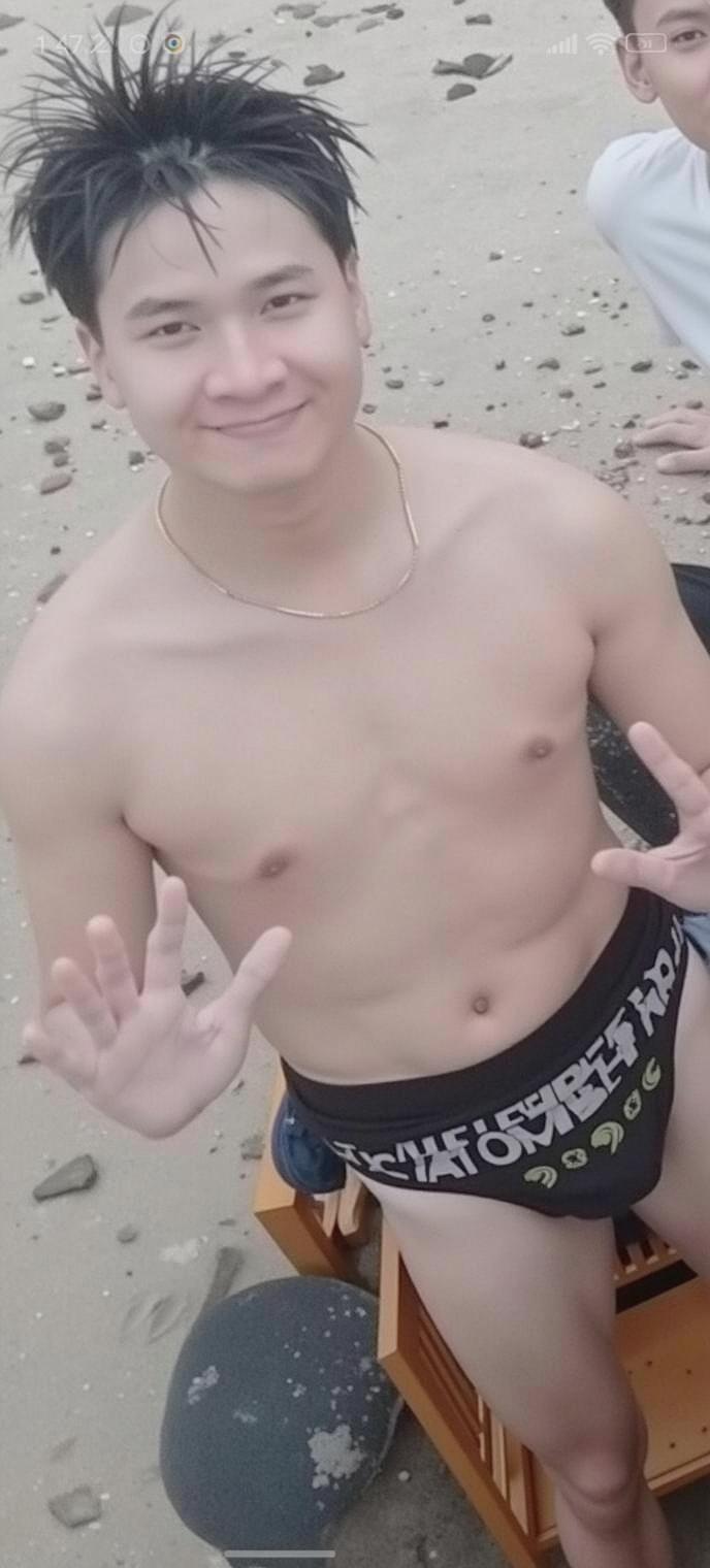 A young man on a beach, smiling and posing for the camera
