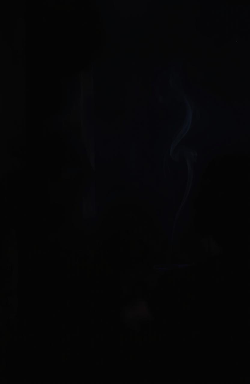 A dimly lit room with a corner shrouded in darkness and wafts of smoke curling through the air