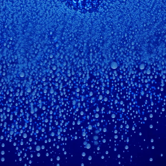 Glistening water droplets cascading against a deep blue background.