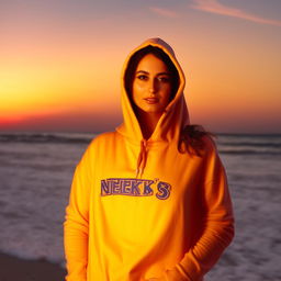 A beautiful Russian woman in a hijab and a hoodie sweatshirt bearing the inscription 'NENK'S', posing on the beach under the beautiful light of the sunset.