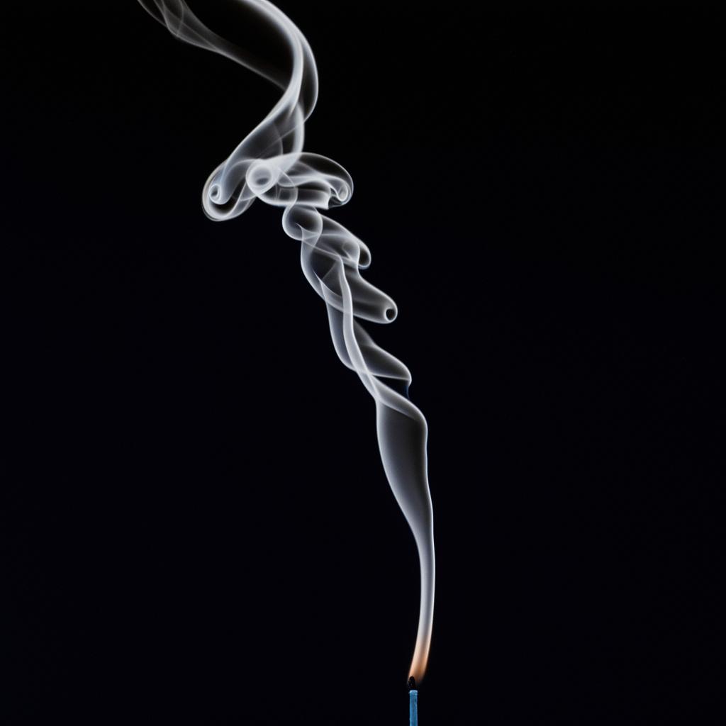 A lit candle emitting smoke that forms the Arabic phrase 'Bismillah al-Rahman al-Rahim', suspended in the air