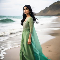 Indian actress Mrunal Thakur at the beach, her attire flowing with the ocean breeze. She is standing near the shoreline, gazing out at the vast ocean.